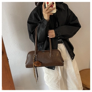 Mirror selfie showing a brown retro shoulder bag with a cute plush bear keychain