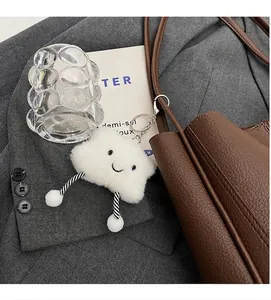 Close-up of a white plush cloud charm with striped legs on a brown leather handbag
