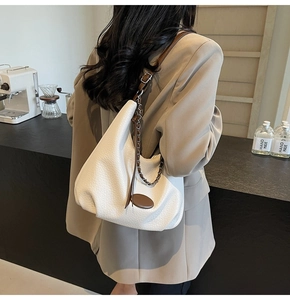 Detailed back view of model wearing white litchi pattern half-moon shoulder bag with chain
