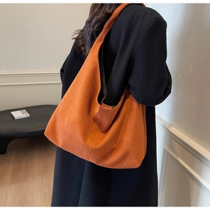 Detailed view of caramel suede tote bag featuring central vertical stitching and a soft structure