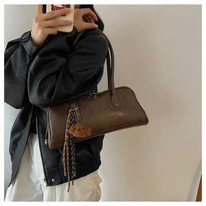 Brown leather baguette bag with teddy bear charm shown in a mirror selfie style