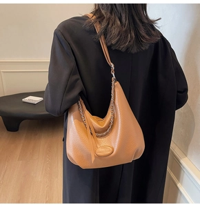 Brown pebbled leather hobo bag with silver chain detail shown on a model's shoulder