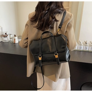 Close-up of black vintage leather backpack with embossed text and gold metal buckles