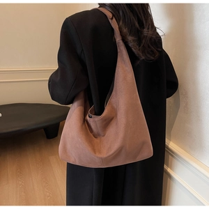 Vue détaillée d'un grand cabas en daim marron porté par un mannequin en intérieur
