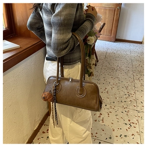 Detail of deep brown retro leather baguette bag with a cute plush bear charm accessory