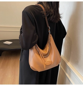 Brown lychee texture hobo bag with silver chain detail on model shoulder for fashion look