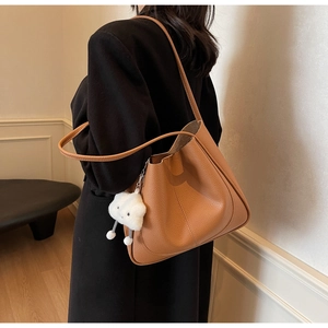Detailed shot of brown pebble grain shoulder bag with a white fluffy cloud charm
