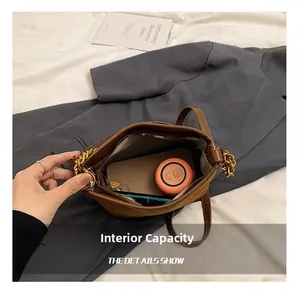 Internal capacity of the brown bucket bag showing phone, powder, and lipstick storage