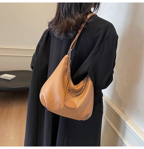 Detail of caramel leather tote bag featuring lychee texture and metallic chain decoration