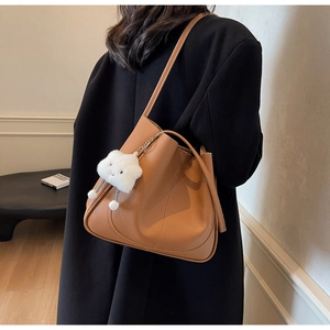 Detail of caramel lychee leather shoulder bag with a cute white cloud plush pendant