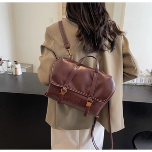 Detailed view of wine red leather tote bag with gold buckles and embossed text logo