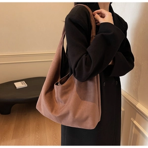 Detail of a large matte suede tote bag in vintage reddish-brown worn by a model