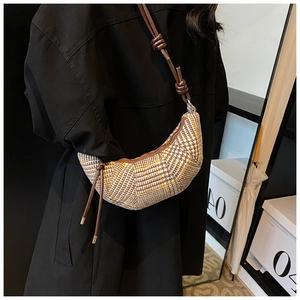 Dettaglio borsa a tracolla pied-de-poule con cinturino in pelle annodato su cappotto nero