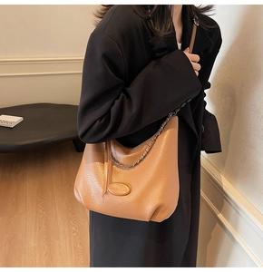 Detail of camel large hobo bag with pebble leather texture and metal chain accent