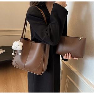 Detail of dark brown lychee leather tote bag with matching pouch and plush charm
