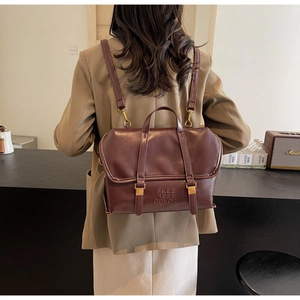 Detail showing vintage brown faux leather backpack with embossed text and gold hardware