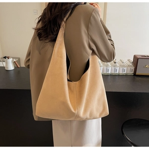 Détail d'un grand cabas en daim marron avec large bandoulière porté par un mannequin