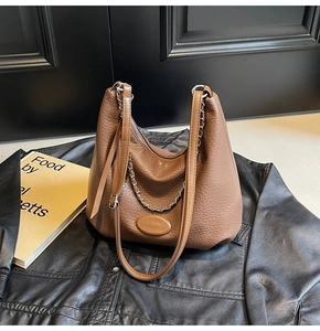 Close-up of brown litchi pattern leather dumpling bag with silver chain and zipper