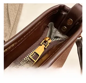 Detail of dark brown leather bucket bag with retro bronze zipper and stitching