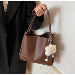 Detail of dark brown lychee leather tote bag with cute cloud plush charm accessory