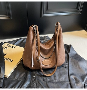 Close-up of brown lychee-patterned leather bag with silver chain and metal hardware