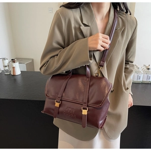 Detail of burgundy vintage tote bag with gold buckle and adjustable crossbody strap