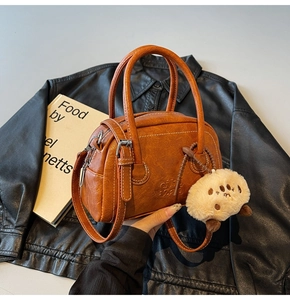 Detail einer karamellbraunen Bowlingtasche aus PU-Leder mit Plüschschaf-Anhänger