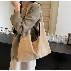 Détail d'un sac hobo en daim kaki avec surpiqûres épaisses dans un café chic