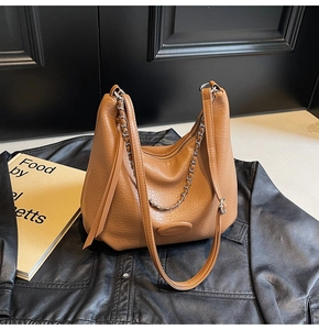 Close-up of brown lychee grain leather dumpling bag with decorative silver metal chain