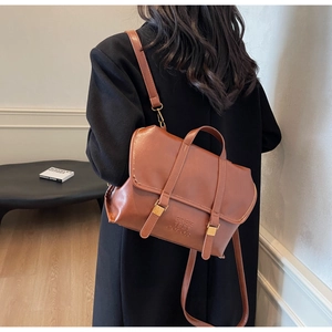 Detailed back view of vintage caramel brown leather backpack with gold buckle and embossed text