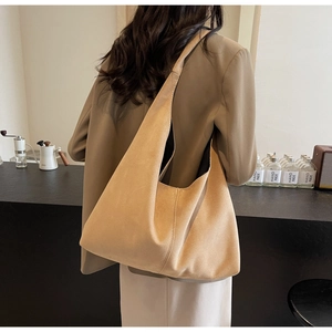 Detail view of large khaki suede tote bag worn on shoulder in a retro aesthetic scene