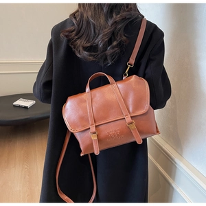 Close-up of caramel leather tote bag with buckle straps and embossed FREE 1981 COLOR text