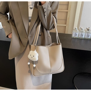 Detail of beige lychee grain tote bag featuring a cute white cloud plush pendant