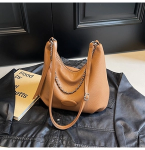 Macro view of caramel litchi grain texture on the croissant shoulder bag with metal chain