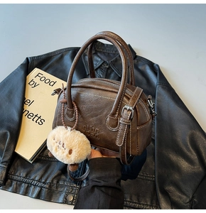 Detailaufnahme der dunkelbraunen Vintage-Bowlingtasche mit Lederstruktur und Anhänger