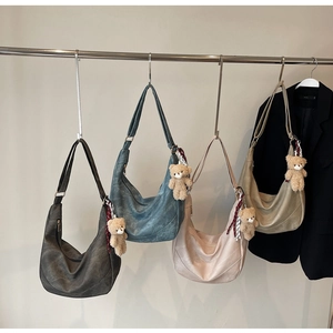 Detailansicht großer Hobo-Taschen in vier Farben mit Plüschbären-Anhänger