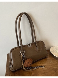 Retro dark brown matte leather baguette bag with a plush bear charm on a wooden table