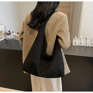 Gros plan du grand sac hobo noir minimaliste avec large bandoulière sur un mannequin