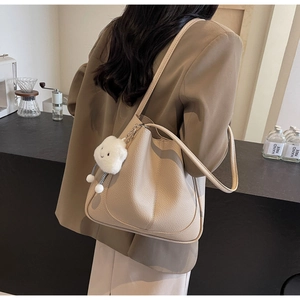 Close-up of beige lychee texture leather tote bag with white cloud plush charm detail