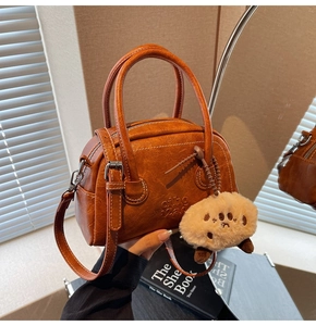 Detail der karamellbraunen Bowlingtasche aus Kunstleder mit Doppelgriffen und Anhänger
