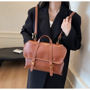 Close-up of brown leather tote bag with FREE 1981 COLOR embossing and retro strap details