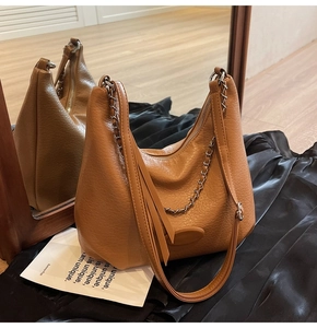 Detail of caramel hobo bag featuring litchi texture, metal chain, and detachable strap