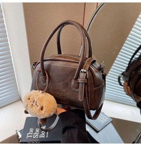 Detail der braunen Vintage-Bowlingtasche aus PU-Leder mit Prägung und Plüsch-Anhänger