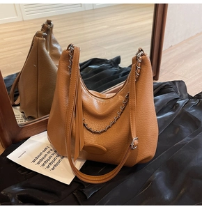 Detail of brown litchi leather hobo bag with silver chain and long tassel decoration