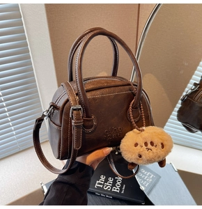 Details der dunkelbraunen Retro-Bowling-Tasche mit PU-Leder und Plüschbär-Anhänger