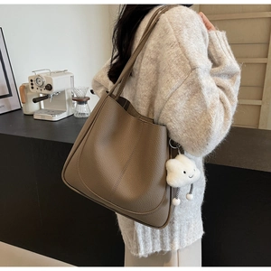 Close-up of elephant gray pebble leather tote with cloud pendant on knit sweater