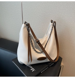 Detail of white lychee-grain hobo bag with brown leather strap and silver metal chain
