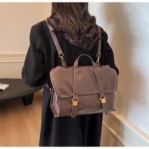Detail showing vintage dark brown faux leather backpack with gold buckle and embossed text