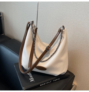 Macro shot of hobo bag featuring pebbled texture, silver chain, and brown leather strap