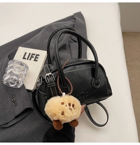 Detail der schwarzen Bowling-Tasche aus PU-Leder mit Kontrastnähten und Plüsch-Anhänger